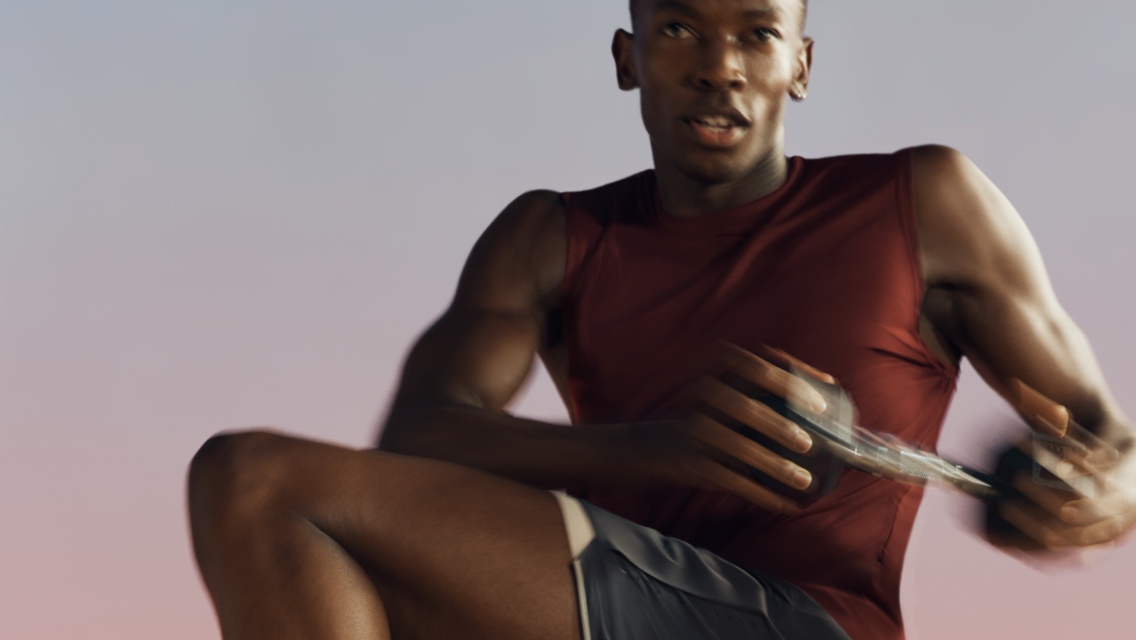 A Shred strength class participant in a standing twist with a dumbbell